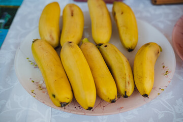A beautiful, vibrant plate brimming with fresh, ripe, and delicious bananas rests elegantly on a nicely arranged table, eagerly waiting to be savored and enjoyed by everyone who is present