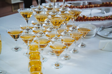 A beautiful pyramid of champagne glasses meticulously filled with sparkling champagne rests elegantly on a table, ready for guests to enjoy a delightful toast during the celebration