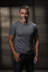Portrait of confident mature man in casual standing on gray background. Happy older middle aged guy smiling. Healthy active, fit mid adult male in 50s.