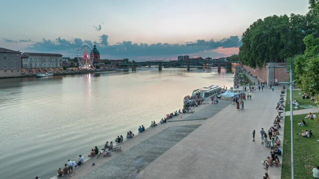Aerial view of Port de la Daurade park along the Garonne River day to night transition timelapse in Toulouse, France. La Grave Hospital with Saint-Pierre Bridge during sunset with colorful clouds
