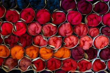 Colorful wool fibers in cardboard rolls arranged in gradient spectrum