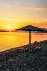 Sunrise on the Beach in the Aegean Sea, Greece with Umbrellas and Sunbeds	