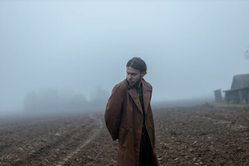 gloomy depressed man in foggy field lonely and sad, male crisis concept