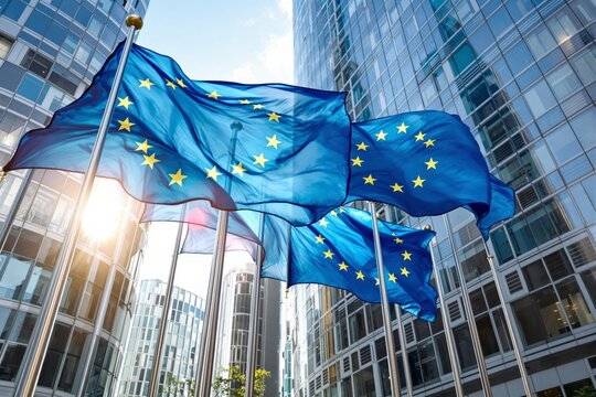 European Union flags waving on flagpoles with modern glass buildings in the background, illuminated by sunlight. Concept of EU politics and diplomacy. Ai generative