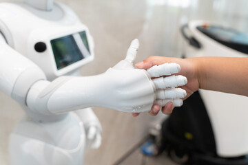 close up view of modern smart robot handshake with human, artificial intelligence concept.