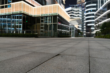 empty ground of modern street with illuminated office buildings at night.