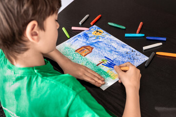 Focused Child in Green T-shirt Drawing with Crayons - Art Therapy for Autism, ADHD, and Digital Detox Concept. boy drawing with colorful pastels. 