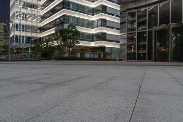 empty ground of modern street with illuminated office buildings at night.
