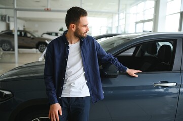 Young man is choosing a new vehicle in car dealership