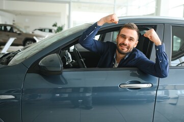 Young man is choosing a new vehicle in car dealership