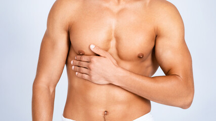 Strong athletic man with muscular naked torso touching his body isolated over white studio wall