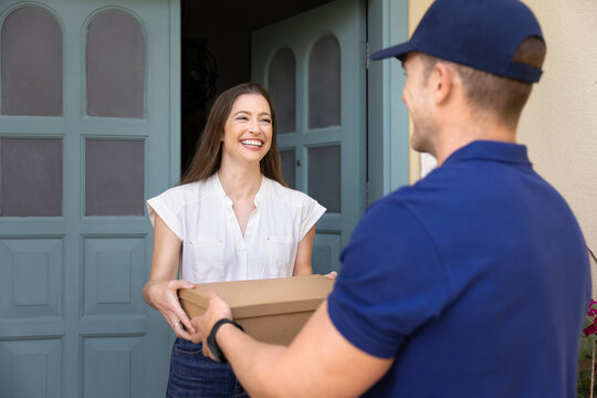 Happy woman get parcel with bought items online or gift from friend standing on porch. Courier in uniform giving package box to client. Customer satisfaction, doorstep delivery services convenience