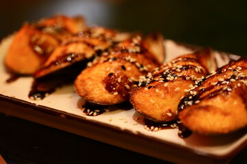 A white plate with sesame seed covered food, perfect for a quick meal or snack.