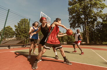 Team of sportsmen playing basketball at outdoor arena