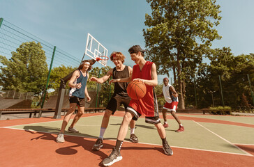 Group of young basketball players practicing their game at outdoor sportsground