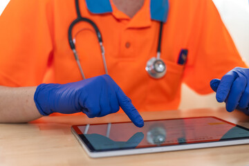 Paramedic wearing blue gloves uses a digital tablet, potentially accessing patient information, medical records, or diagnostic tools, highlighting the integration of technology in modern healthcare