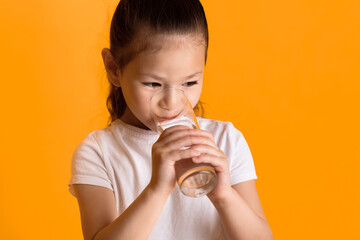 Stay Hydrated Concept. Close up portrait of small asian girl drinking fresh water, isolated over...