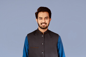 Handsome millennial man of Indian origin smiling over lilac background