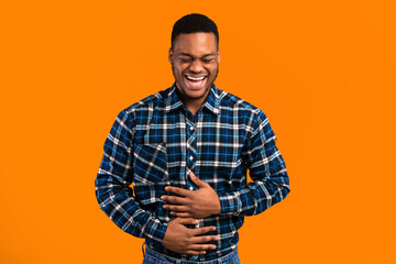 LOL Concept. African Guy Laughing Out Loud Touching Stomach Standing Over Yellow Background. Studio...