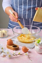 Step by step preparation of Easter cake or other Easter pastries on pink concrete background. Rubbing butter with eggs and sugar. Happy Easter.
