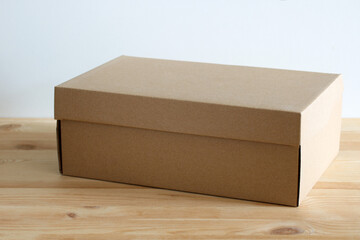 Closed cardboard box sitting on wooden table against white background