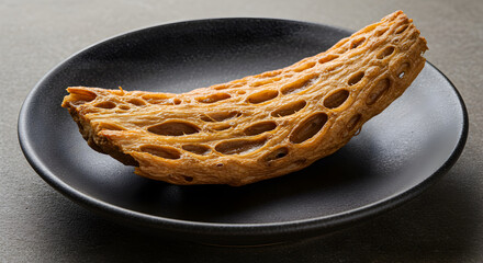 Artisan Crafted Crispy Skirret Root Slice Served on Elegant Black Plate