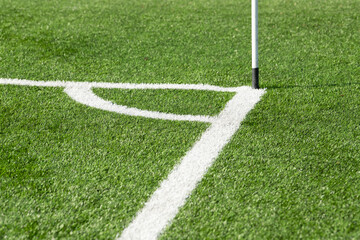 Obraz premium Soccer field markings near the corner flag. White lines on vibrant green grass. Artificial turf.