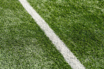 Fototapeta premium Sports field markings on the lawn. A white diagonal line on vibrant green grass. Artificial turf.