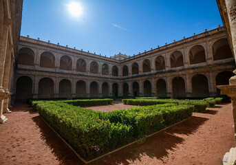 Obraz premium Iconic Spanish Courtyard in Valencia Featuring Architectural Arches and Geometric Hedges Under a Bright Blue Sky