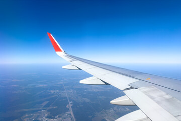 Obraz premium View from the airplane window at a beautiful cloudy sky and the airplane wing. Earth and sky as seen through window of an airplane. Travel concept. Copy space