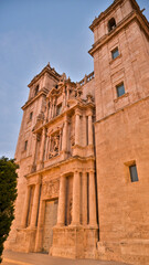Iconic historic facade of Valencia Cathedral in warm evening light highlighting intricate stone carvings, symmetrical towers, and detailed architectural design.