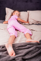 A happy beautiful little girl is lying in bed on a pillow and smiling. Good morning! Healthy sleep.