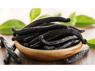 Close up photo showing many vanilla beans in a wooden bowl