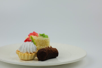 Side view of mini desserts lying on a plate on a white background with space for text. The concept of mini desserts, sweets, confectionery. High quality photo