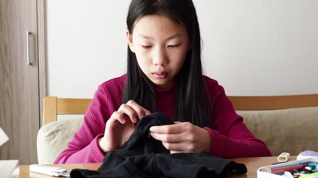 家で服を縫う小学生の女の子の様子