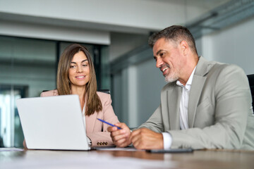 Two professional middle aged business man and woman managers in office. 2 smiling executives using...