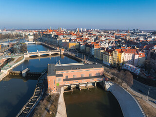 Aerial view of Wroclaw, Poland, showcasing the Oder River, Wroclaw Waterworks, arched bridges, colorful facades, and Wroclaw Cathedral spires.
