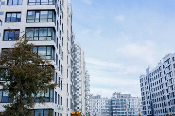 Obraz premium A residential complex with houses of modern architecture in white with gray inserts, large balconies and windows against the blue sky. The concept of apartments for living, city, area of residence