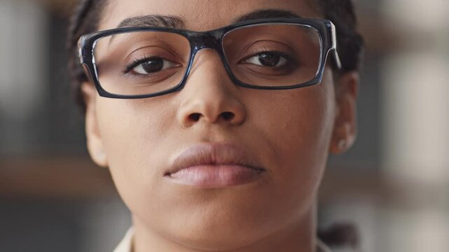 An African American woman with glasses focuses on the camera while teaching online. She embodies a modern approach to remote education, engaging students from her space.