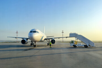 Passenger aircraft with boarding stairs, prepared to taking off on runway, waiting for boarding passengers and baggage before the flight. Airport trip concept.