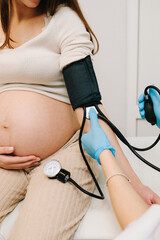 Gynecologist measures blood pressure for pregnant patient in the maternity center. High pressure problem during pregnancy.