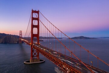 Golden Gate Bridge at dusk in San Francisco, USA. Cars create light trails as they commute across the iconic landmark, connecting the city.