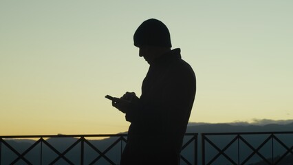 Silhouette Of A Man Scrolling The News On The Phone At Sunset