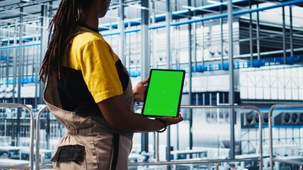Smart factory engineer implements automated workflows using green screen tablet, computerizing manual operations. Technician integrates sensors into production lines using chroma key device, camera A