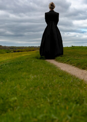 A woman in a black dress is standing on the grass.