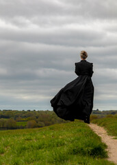 A woman in a black dress is standing on the grass.