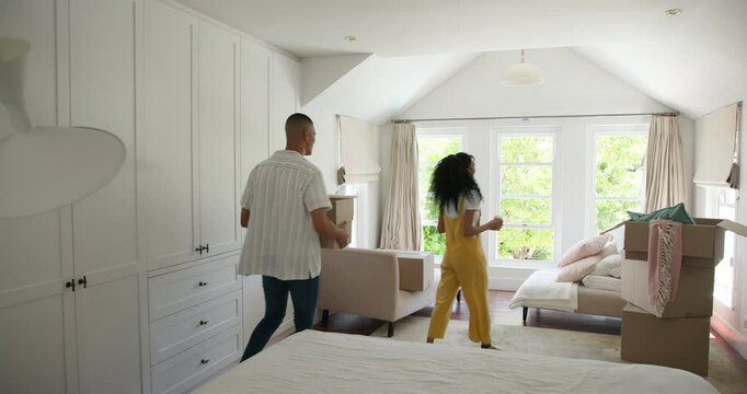 Diverse couple unpacking boxes in bright bedroom, organizing new home together