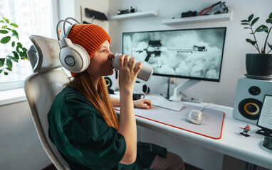 Gamer leans back in an adjustable chair while casually sipping an energy drink. Smart workstation setup supports both focused gameplay and relaxed moments between sessions.