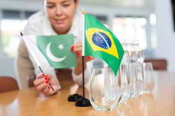 Little flag of Brazil on table with bottles of water and flag of Pakistan put next to it by...