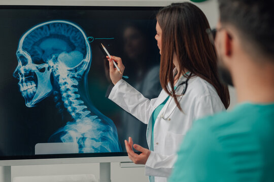 Female doctor explaining skull x ray to medical team on digital display
